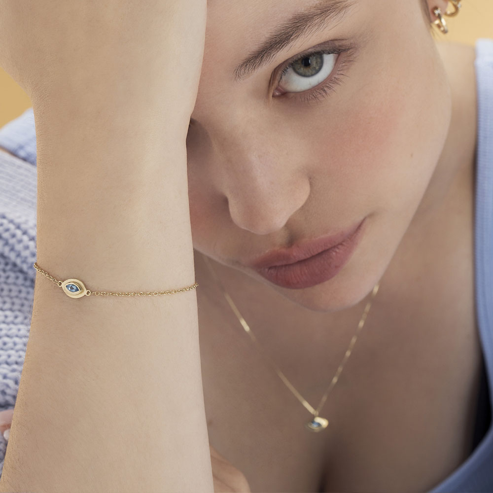 A gold bracelet in the style of the evil eye inlaid with an aquamarine stone in a marquise cut