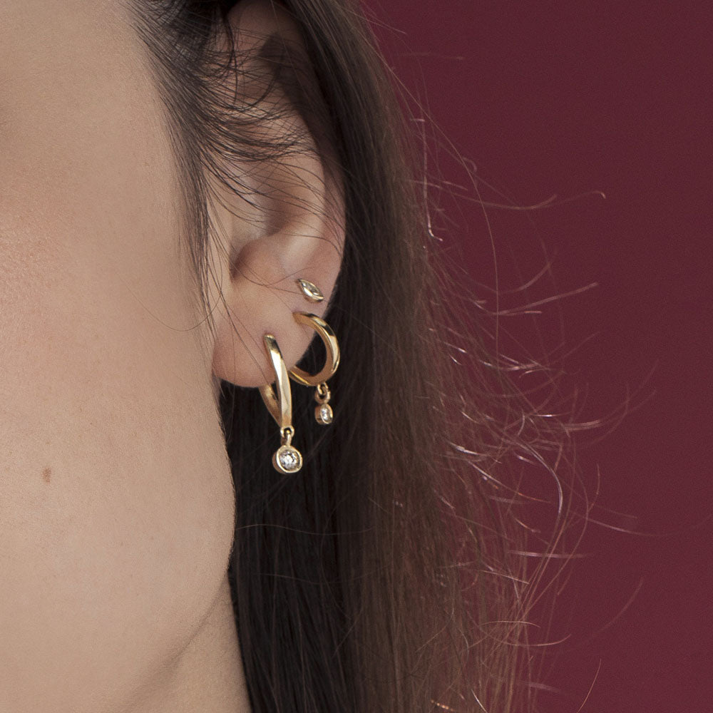 Special elongated hoop earrings, with a swinging diamond in a gold frame