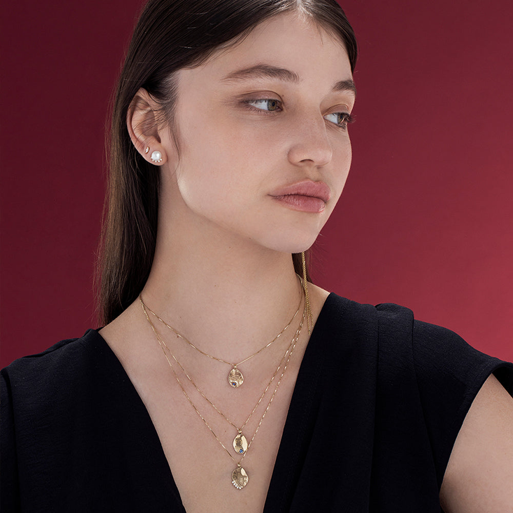 Gold necklace with an amorphous pendant with a sapphire inlaid eye decoration