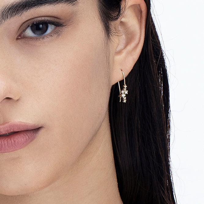 Hanging gold earrings studded with laboratory diamonds of varying sizes