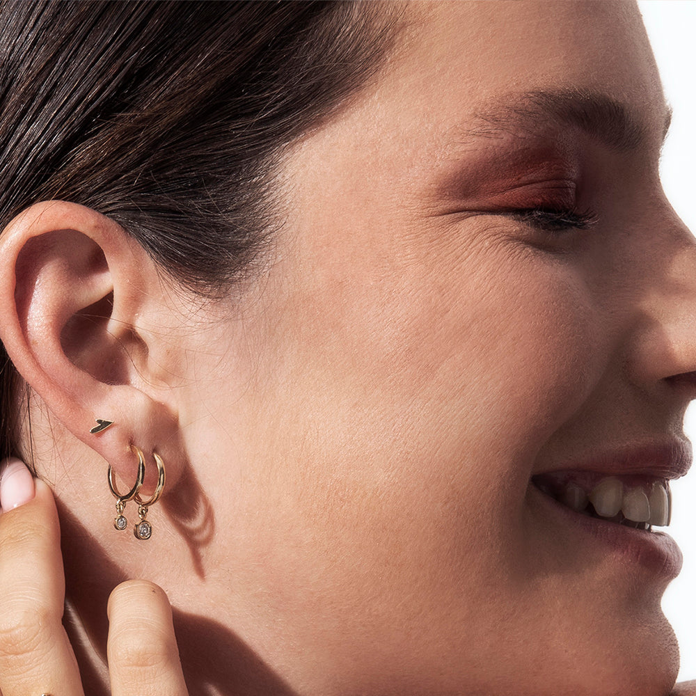 Small tight gold earrings in the shape of a small asymmetric heart