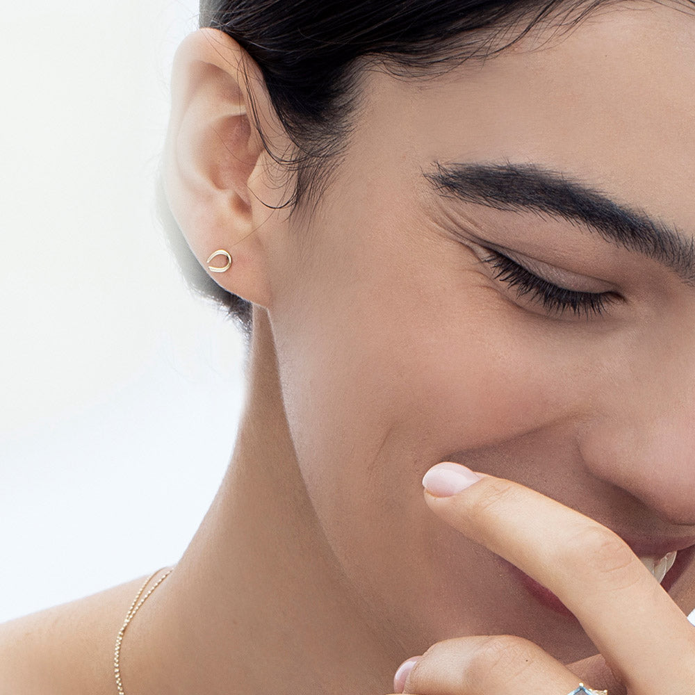Small tight gold earrings in the shape of a horseshoe