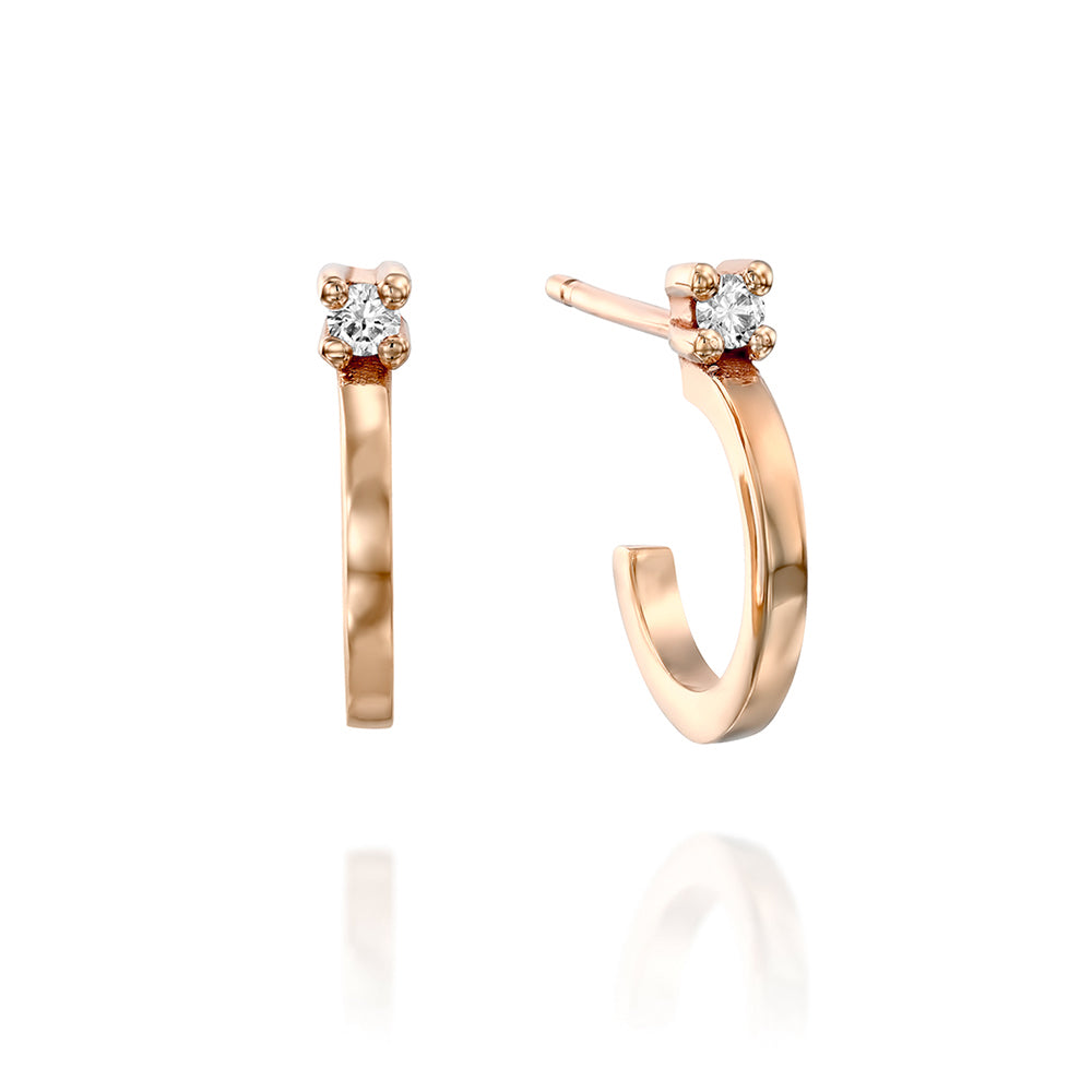 Small gold hoop earrings set with a white diamond close to the ear