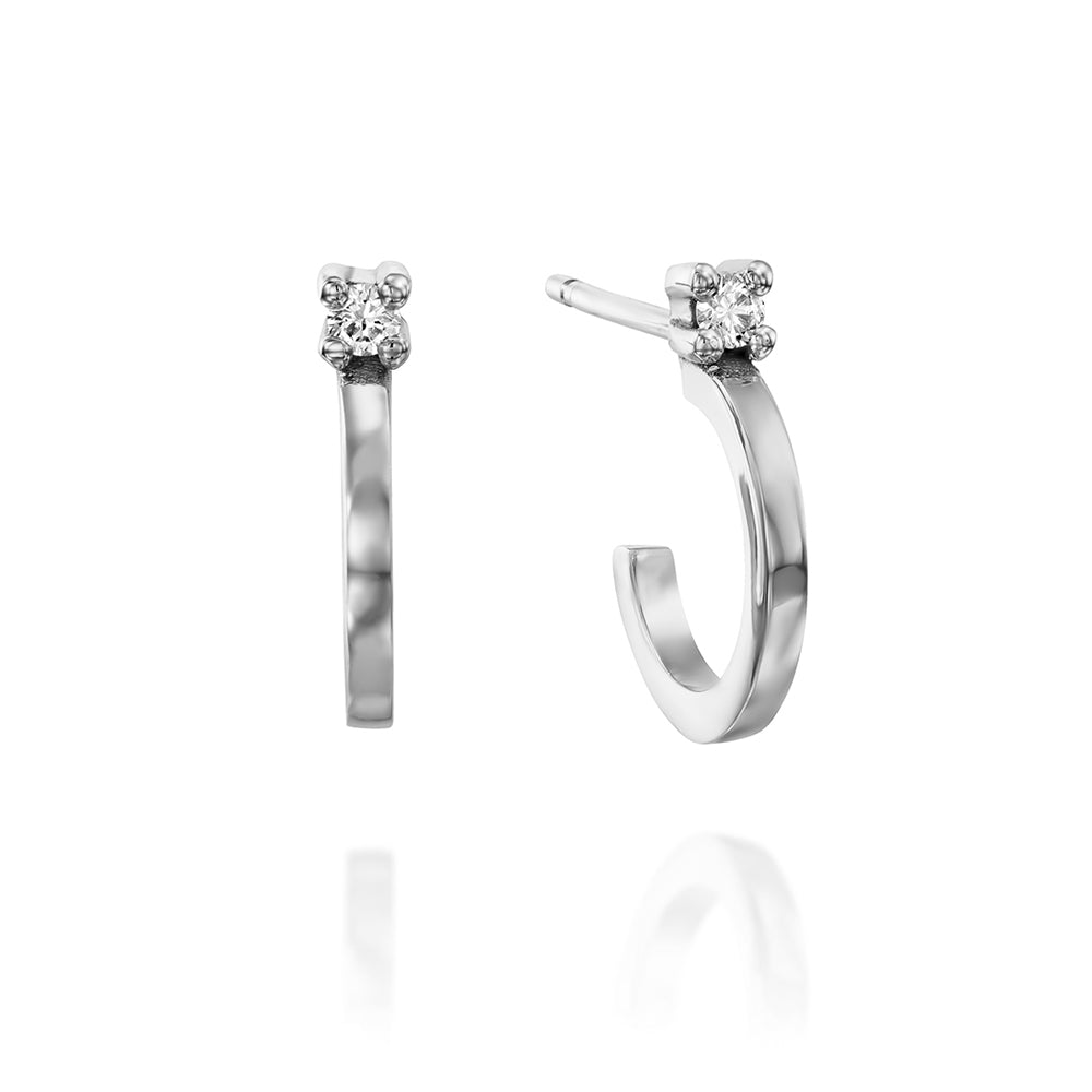 Small gold hoop earrings set with a white diamond close to the ear