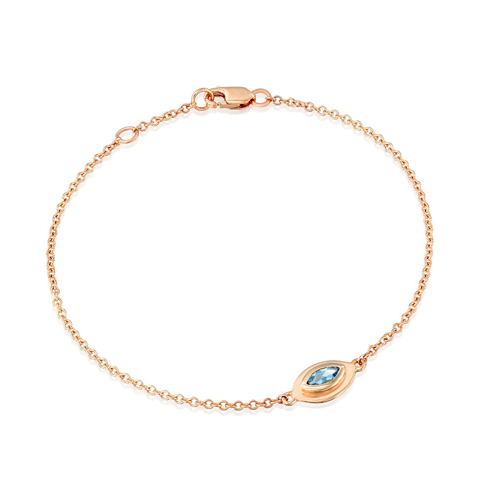 A gold bracelet in the style of the evil eye inlaid with an aquamarine stone in a marquise cut