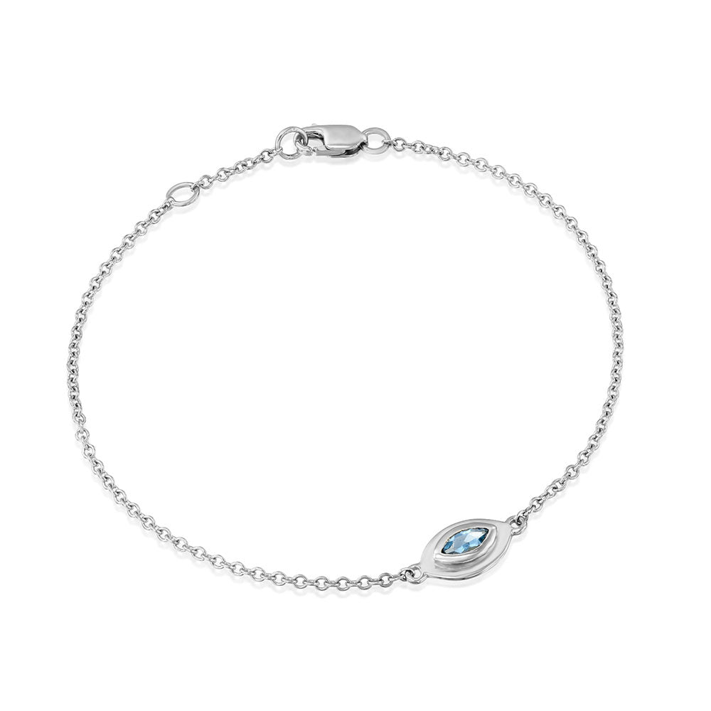 A gold bracelet in the style of the evil eye inlaid with an aquamarine stone in a marquise cut