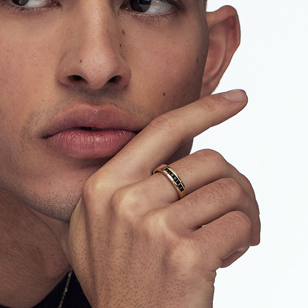 A wide gold ring for men inlaid with onyx in a line princess cut