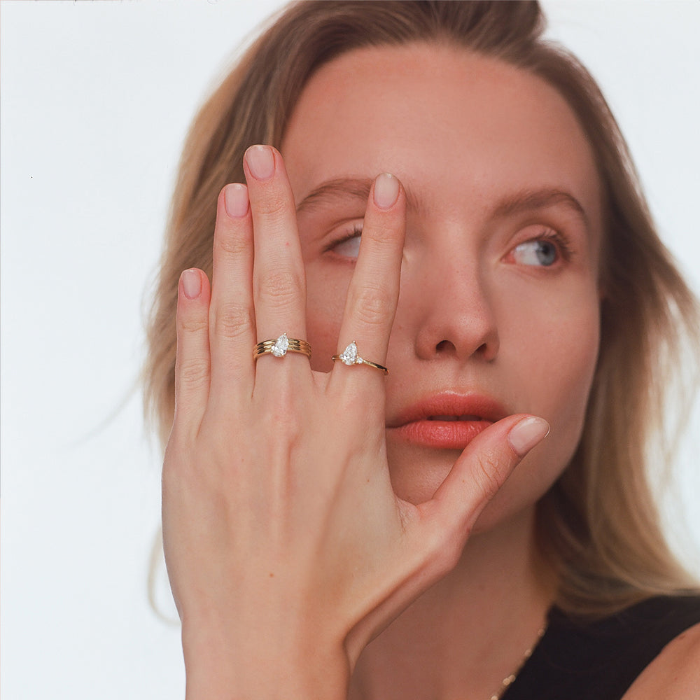 A wide gold ring set with a drop-cut lab diamond