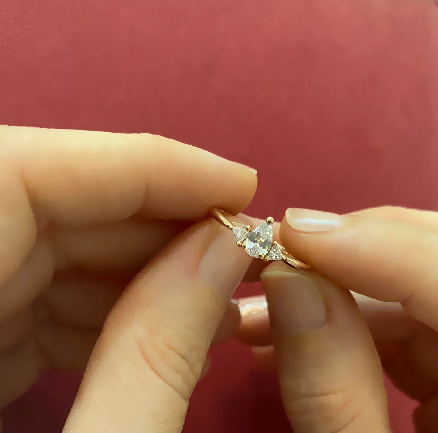 An engagement ring set with a central drop-cut diamond and triangular-cut diamonds on the sides