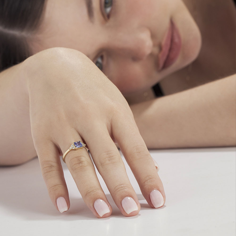A gold ring set with Tanzanite Princess and 6 sided diamonds