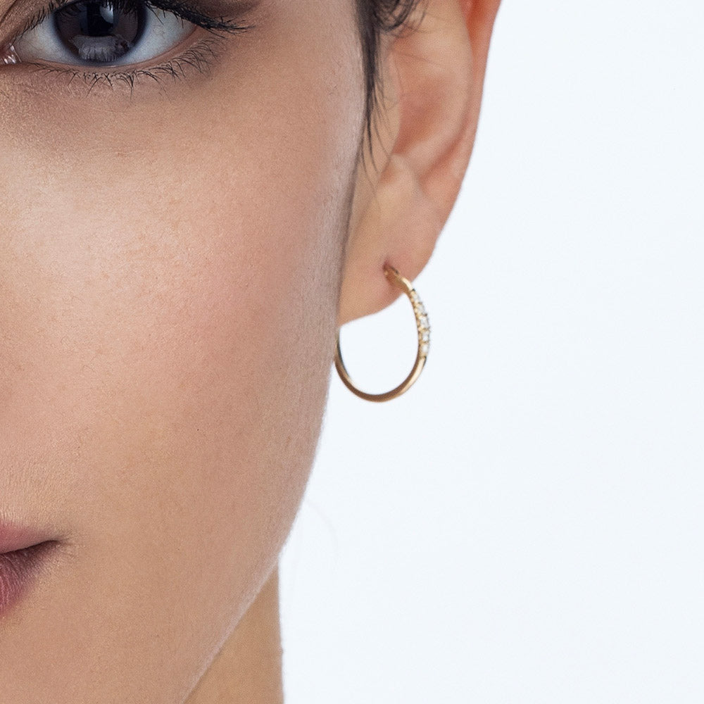 Delicate gold hoop earrings set with a row of 5 diamonds of different sizes