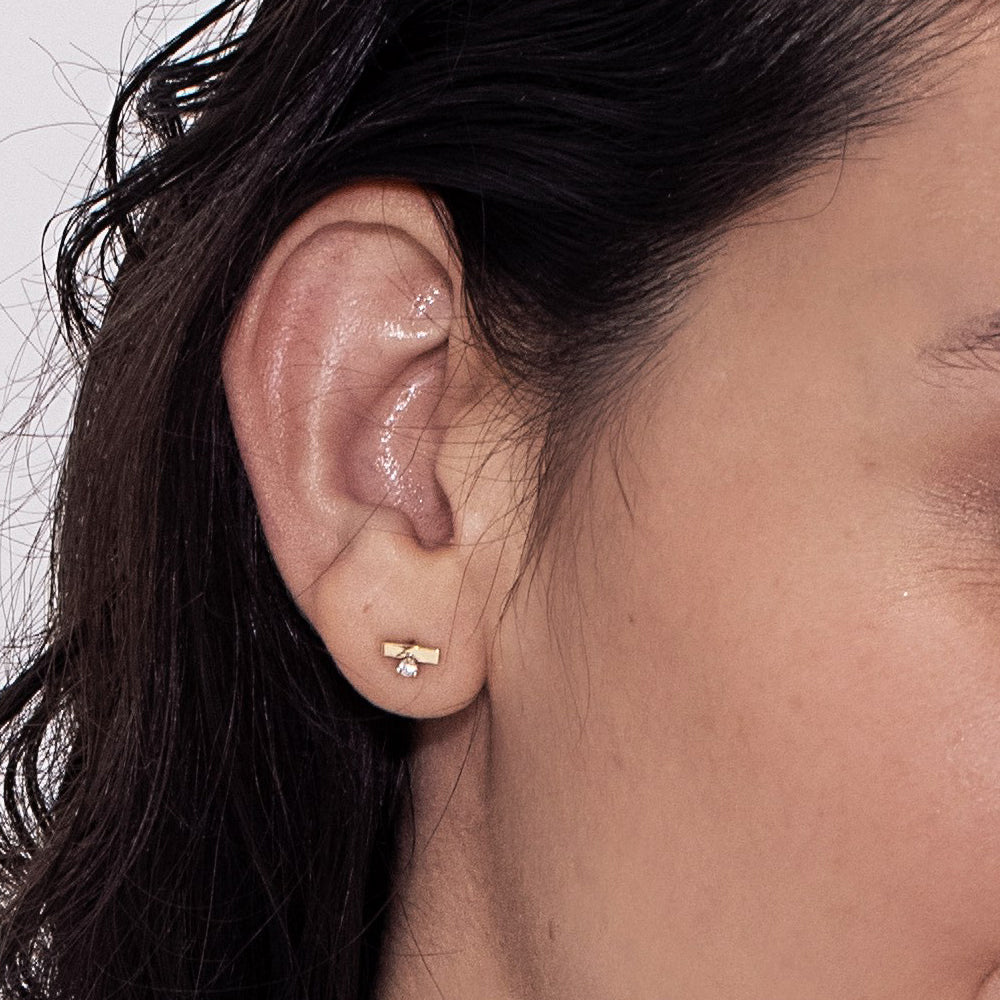 Gold earrings, tight, small, in the form of a stripe, set with a diamond