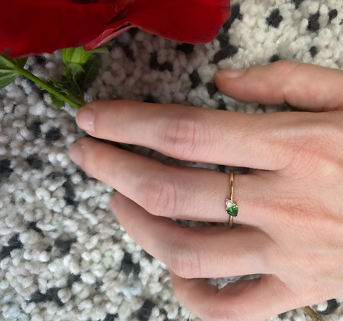 A gold ring set with a diamond and green tourmaline in a trillion cut