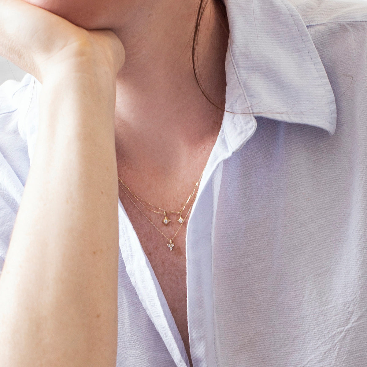 A delicate gold chain with a large square pendant and a 4-point diamond in the center