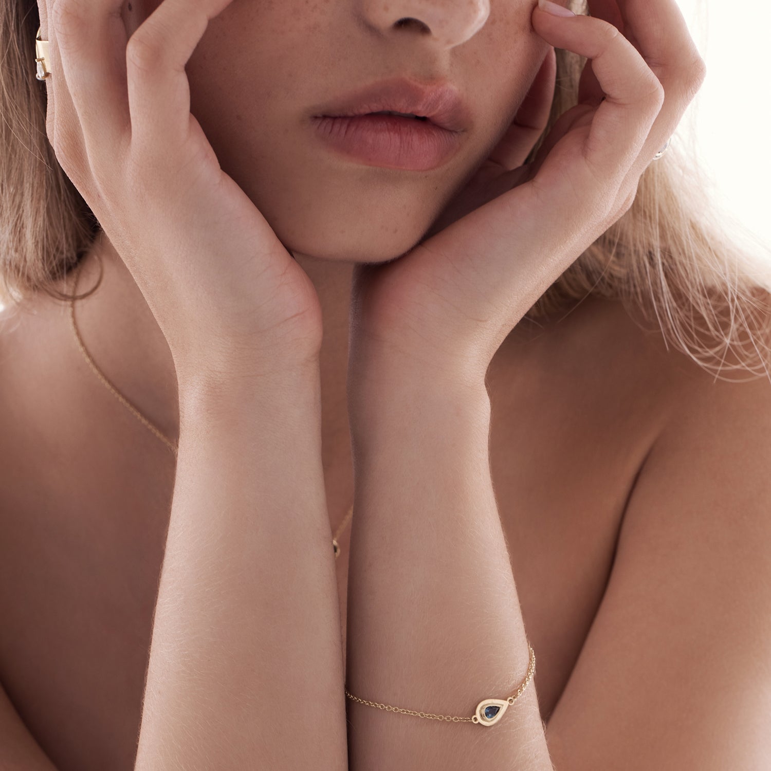 A gold bracelet inlaid with a gold pendant in the shape of a drop and in the center London Blue Topaz