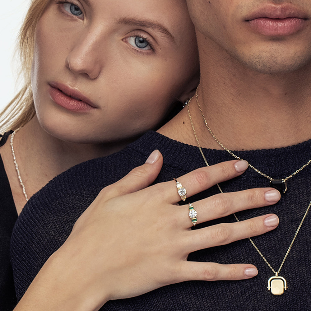 An engagement ring in gold and laboratory diamonds in a unique design of round diamonds and emeralds