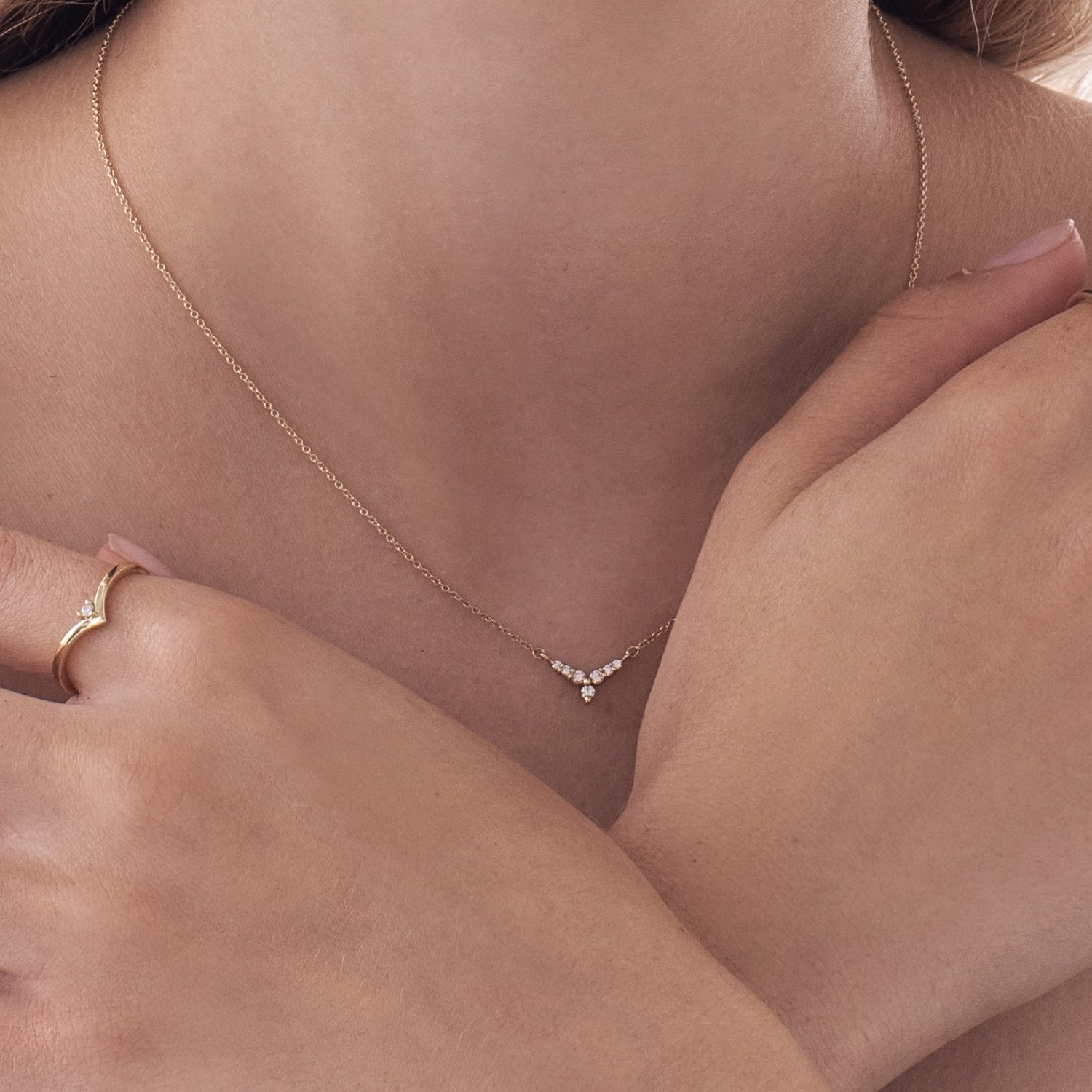 A gold necklace with a V-shaped pendant studded with diamonds reminiscent of a flower