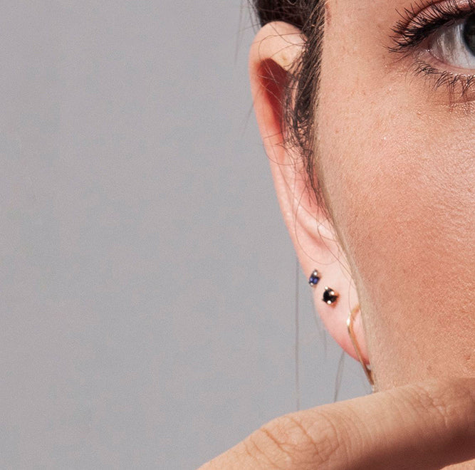Gold solitaire earrings studded with black diamonds