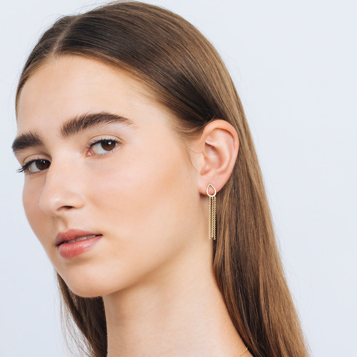 Drop-shaped gold earrings with hanging chains studded with diamonds