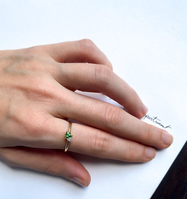 A gold ring set with a diamond and green tourmaline in a trillion cut