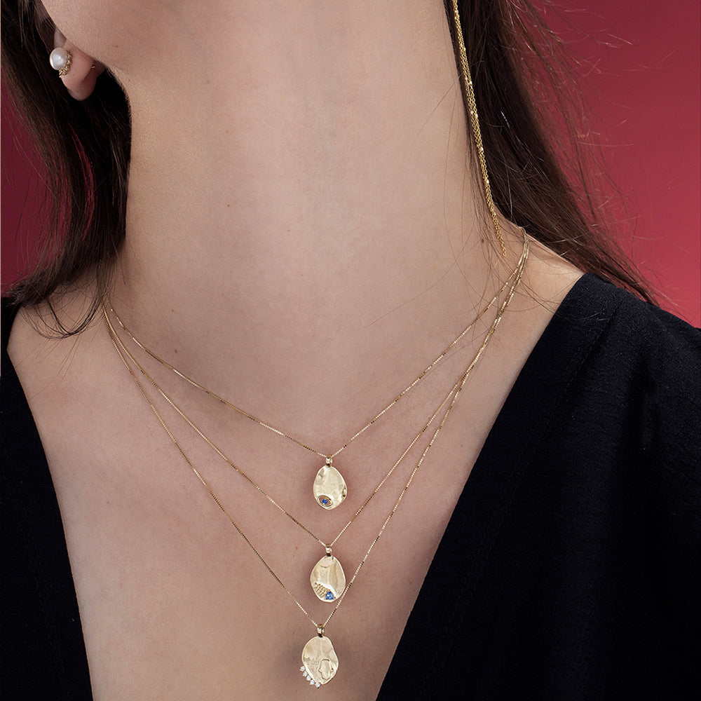 Gold necklace with an amorphous pendant with a sapphire inlaid eye decoration