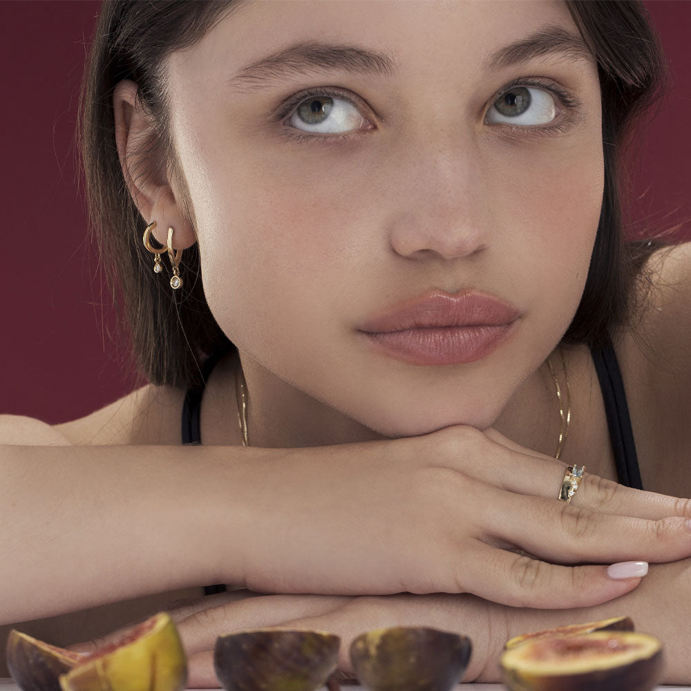 Small gold hoop earrings with a 4-point diamond pendant in a gold frame
