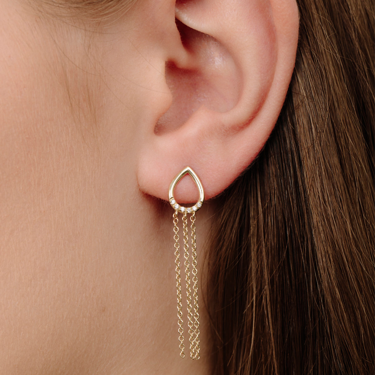 Drop-shaped gold earrings with hanging chains studded with diamonds