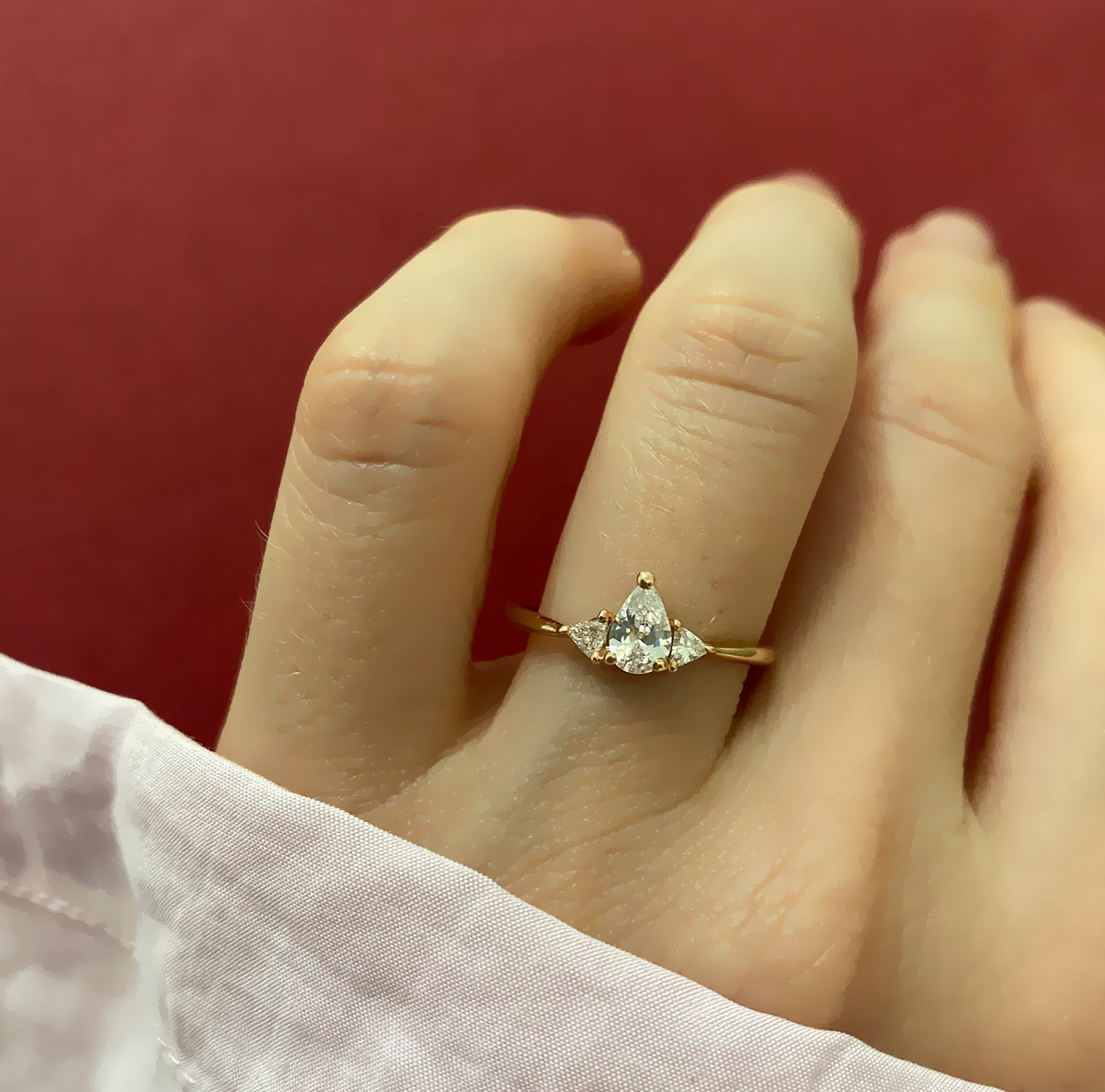 An engagement ring set with a central drop-cut diamond and triangular-cut diamonds on the sides