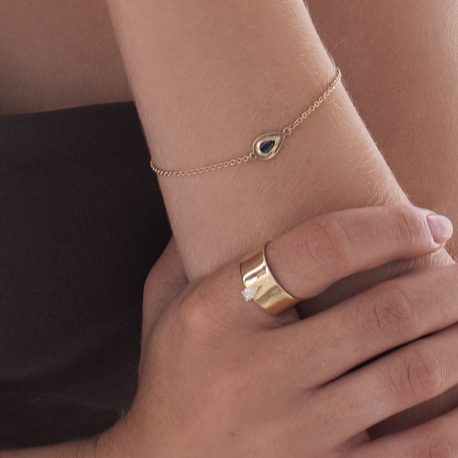 A wide gold ring set with a drop cut diamond