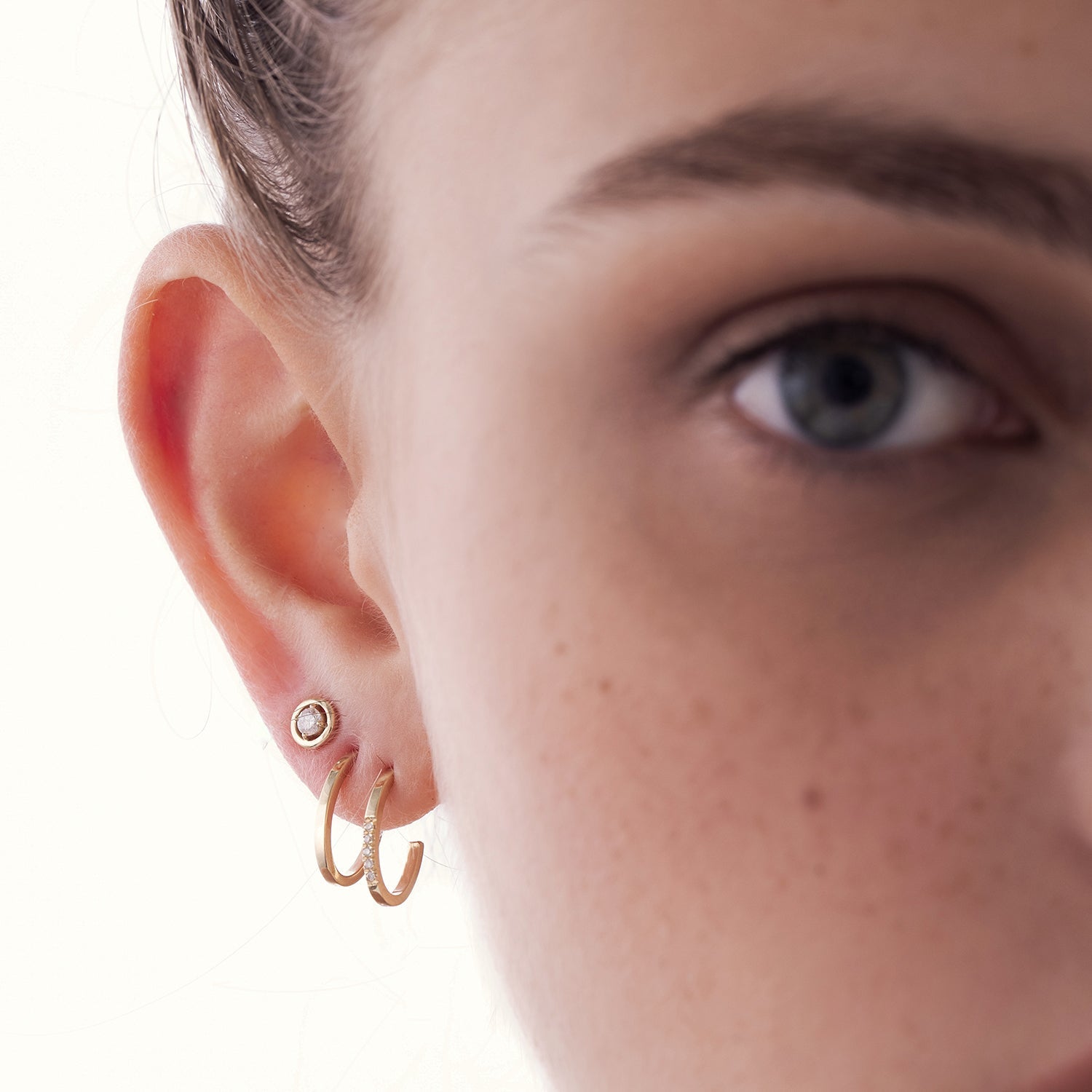 Oval shaped gold hoop earrings studded with diamonds