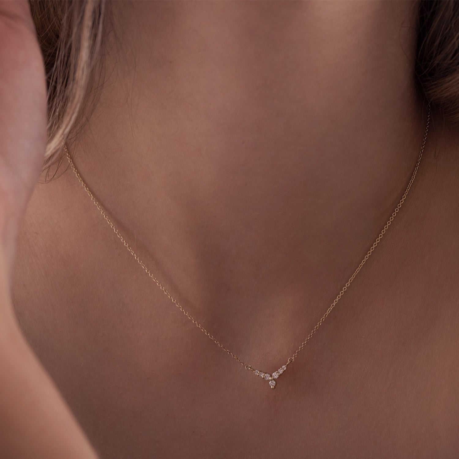 A gold necklace with a V-shaped pendant studded with diamonds reminiscent of a flower