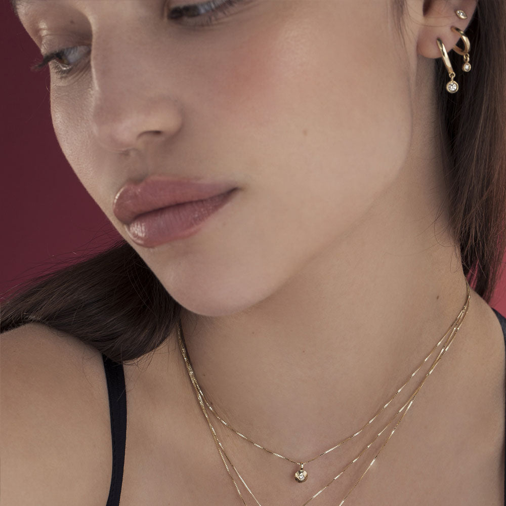 Special elongated hoop earrings, with a swinging diamond in a gold frame