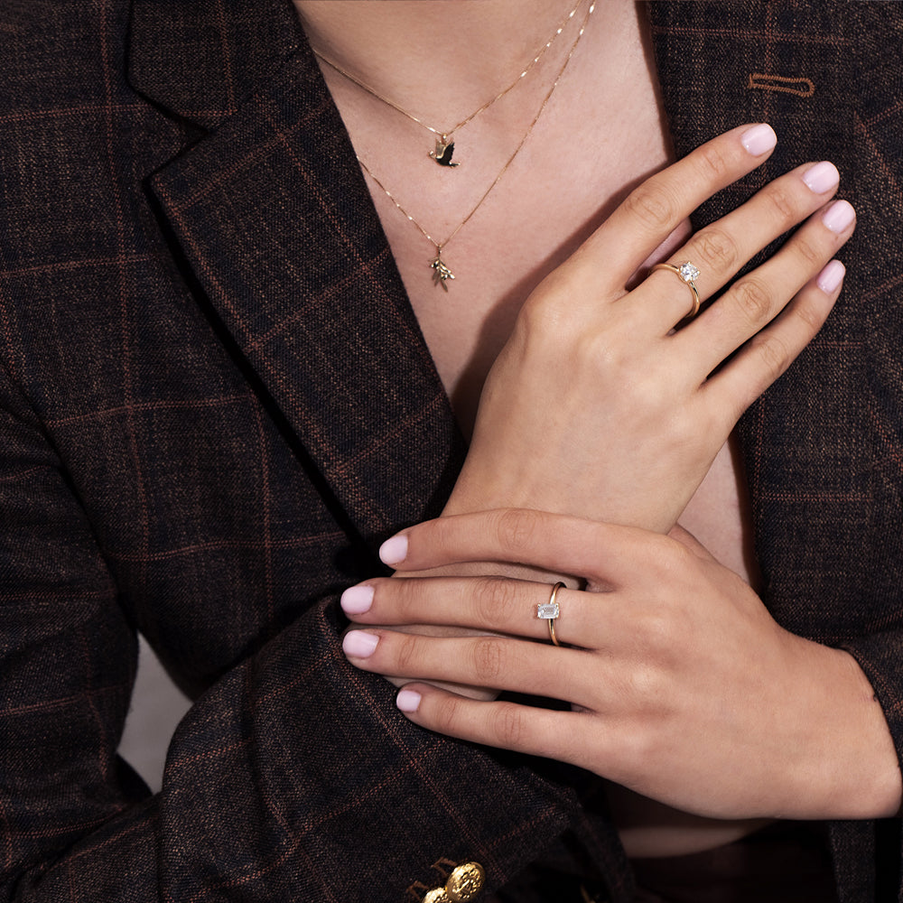 A gold necklace with a dove of peace pendant and an olive leaf