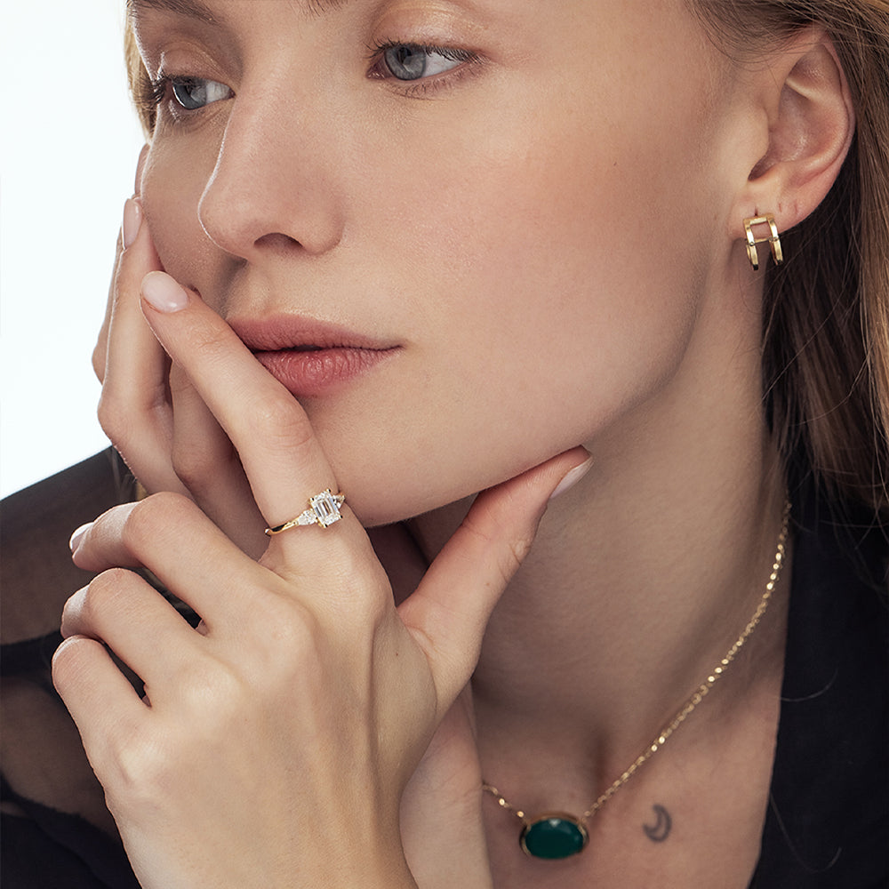 An engagement ring set with laboratory diamonds. Emerald cut central diamond and two drops