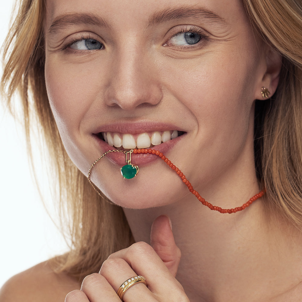 A gold chain combined with natural coral, in the center a green onyx pendant with an oval cut