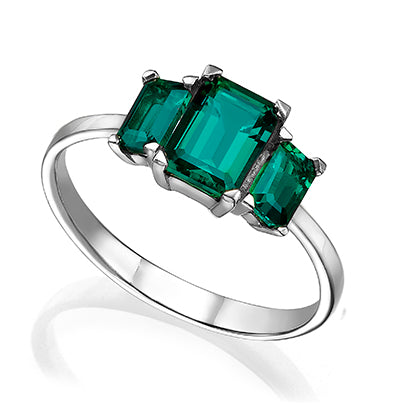 A gold ring set with three rectangular Chatham emeralds