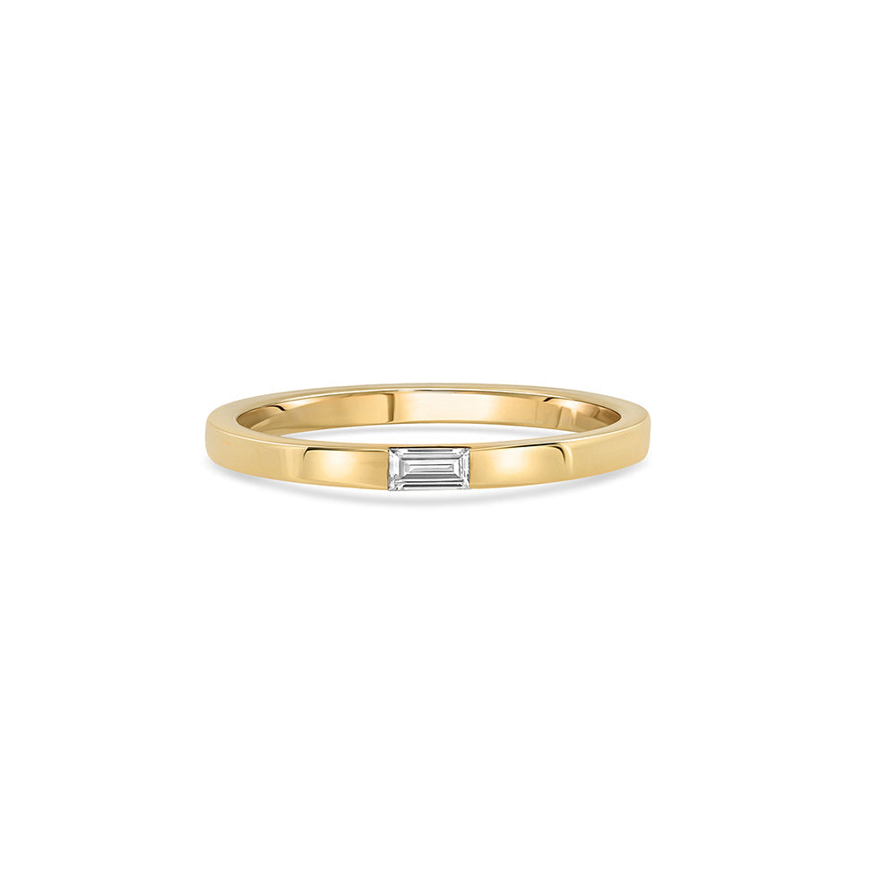 A thin flat gold ring set with a baguette-cut laboratory diamond