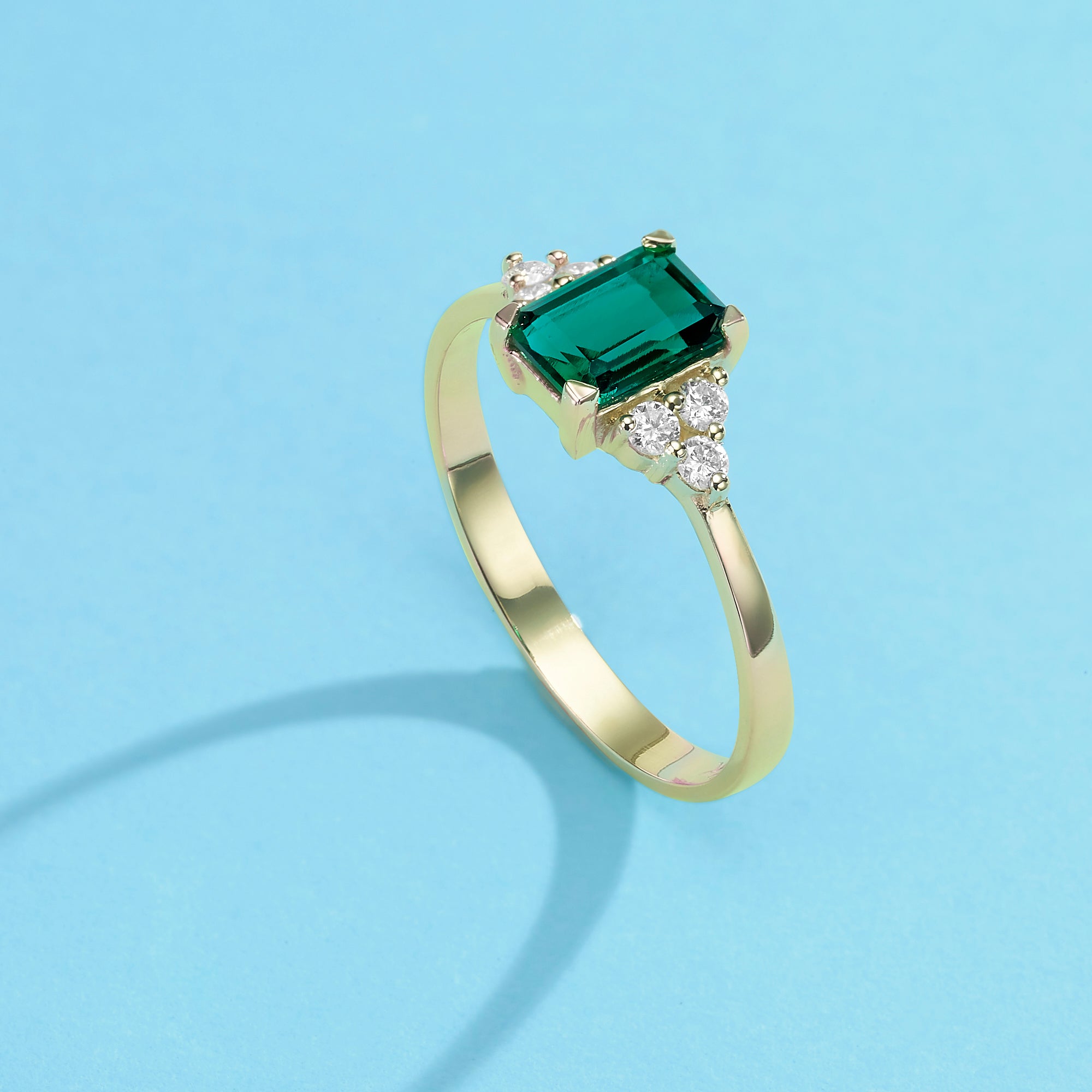 An engagement ring set with a rectangular lab emerald and 6 sided diamonds